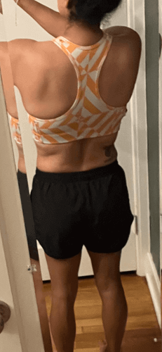 PCOS Sisters A woman taking a selfie in her sports bra from her back, showing her transformation after her PCOS Weight Loss journey