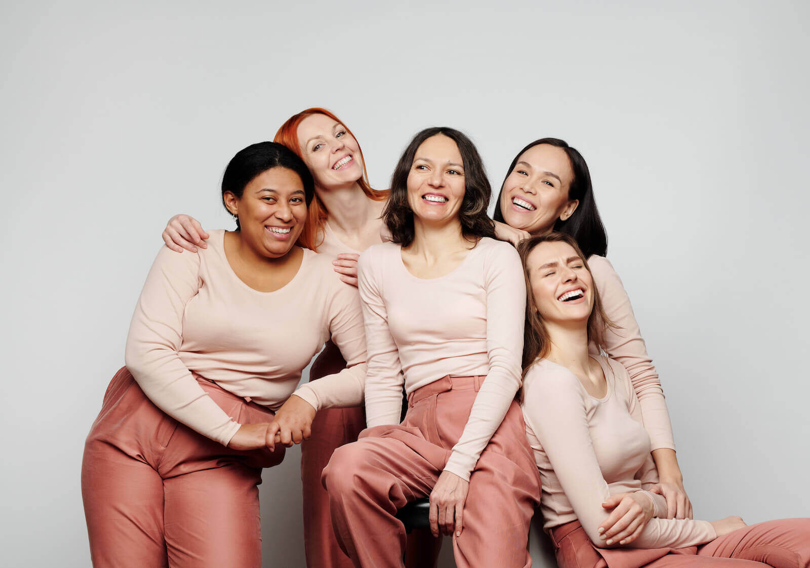 PCOS Sisters A group of women in pink tops are laughing together.