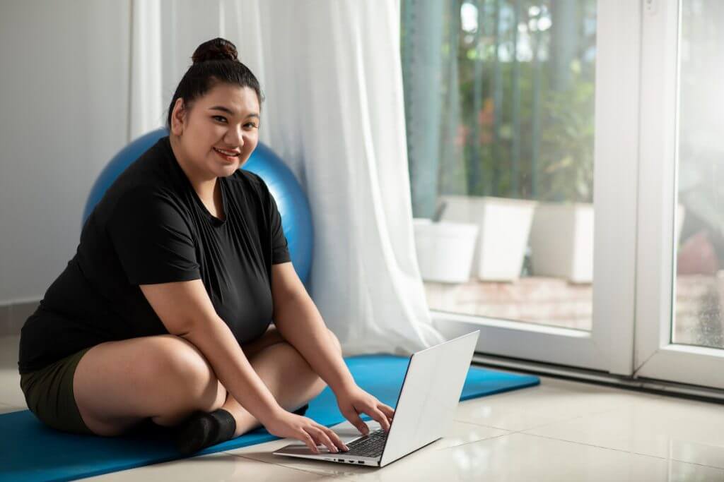 A woman sitting on the ground using her laptop.